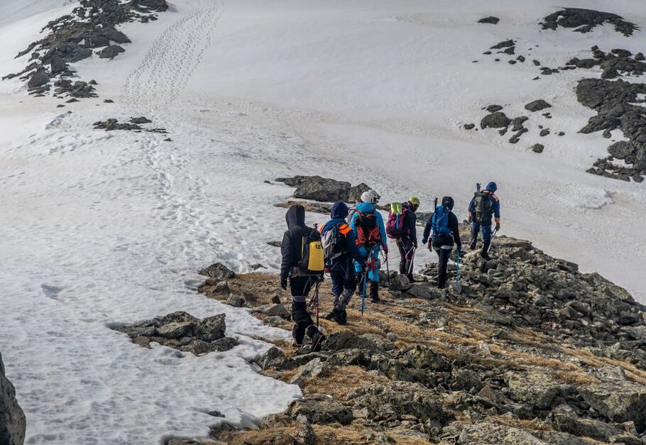 Adventurous group hiking on a snowy mountain ridge during winter, showcasing teamwork.