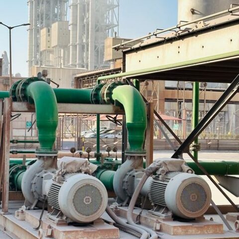 Outdoor scene of industrial machinery with distinct green pipes at a large factory.