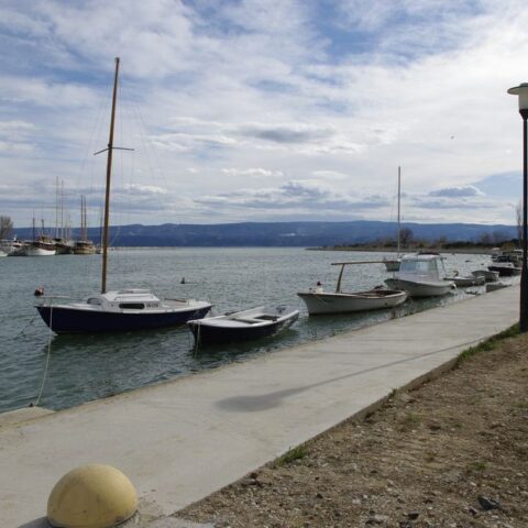 Tranquil scene of boats moored at waterfront promenade with mountains in the background in Omiš, Croatia.