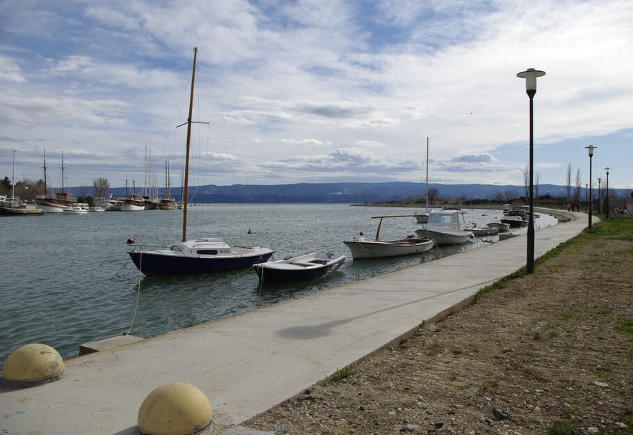 Tranquil scene of boats moored at waterfront promenade with mountains in the background in Omiš, Croatia.